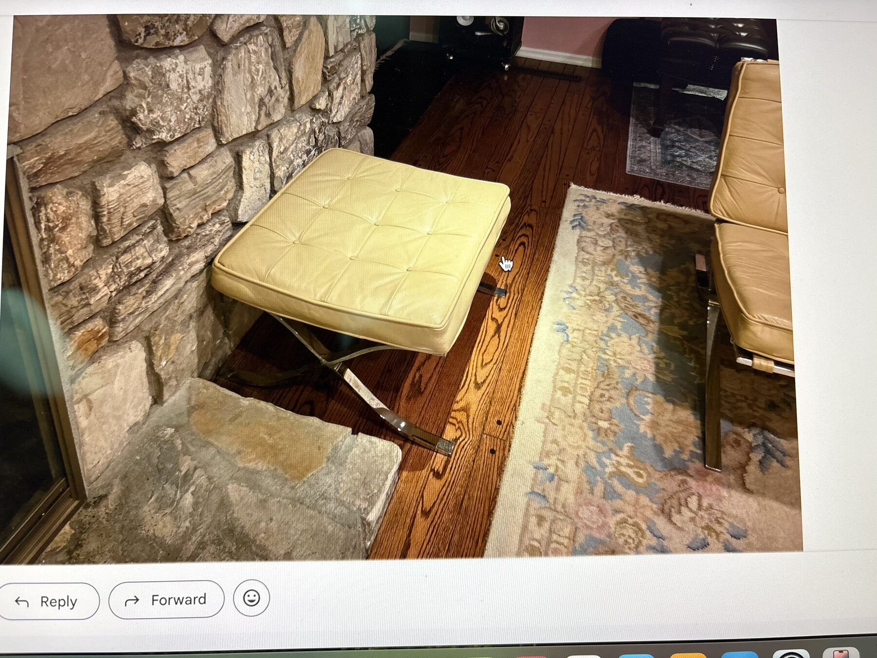Before restoration detail of a Barcelona chair and ottoman near a stone fireplace